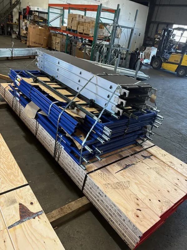 Blue scaffold frames, aluminum platforms and planks strapped on a pallet in a warehouse